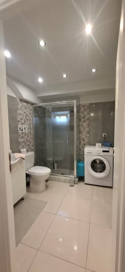 Bathroom with washing machine and walk-in shower